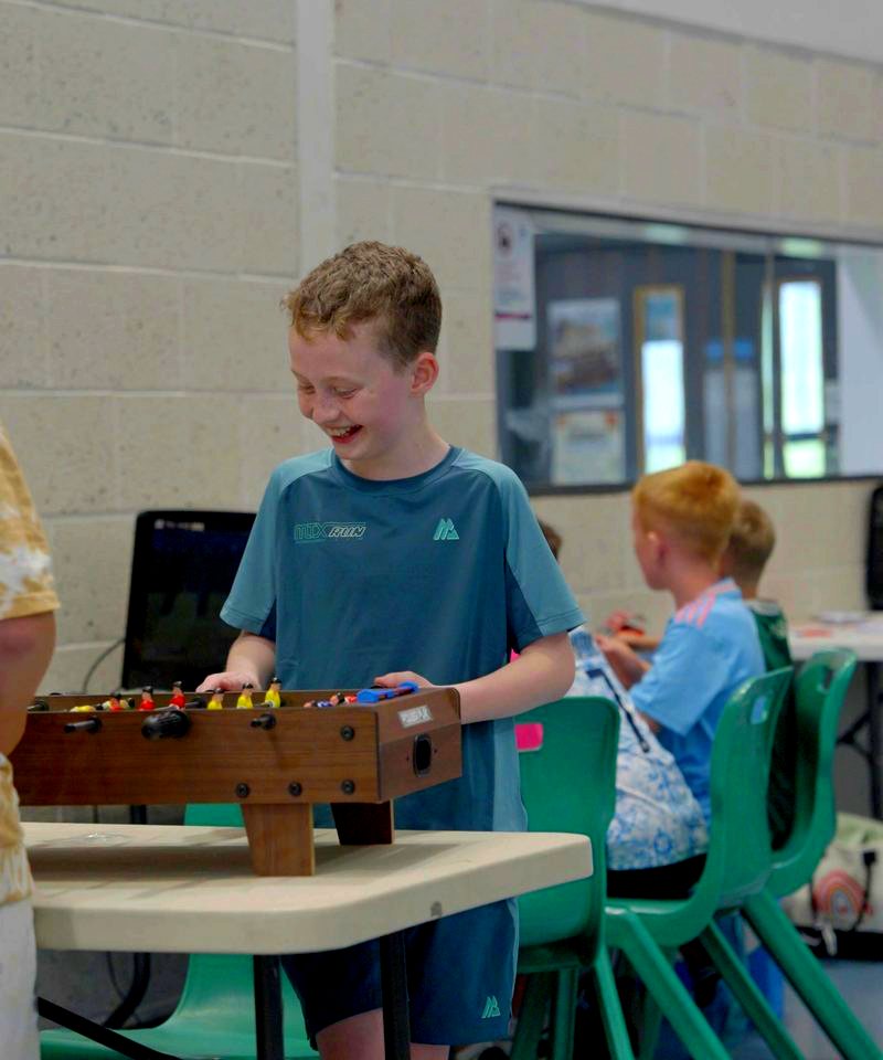 A member grinning over a game of table football at the youth club