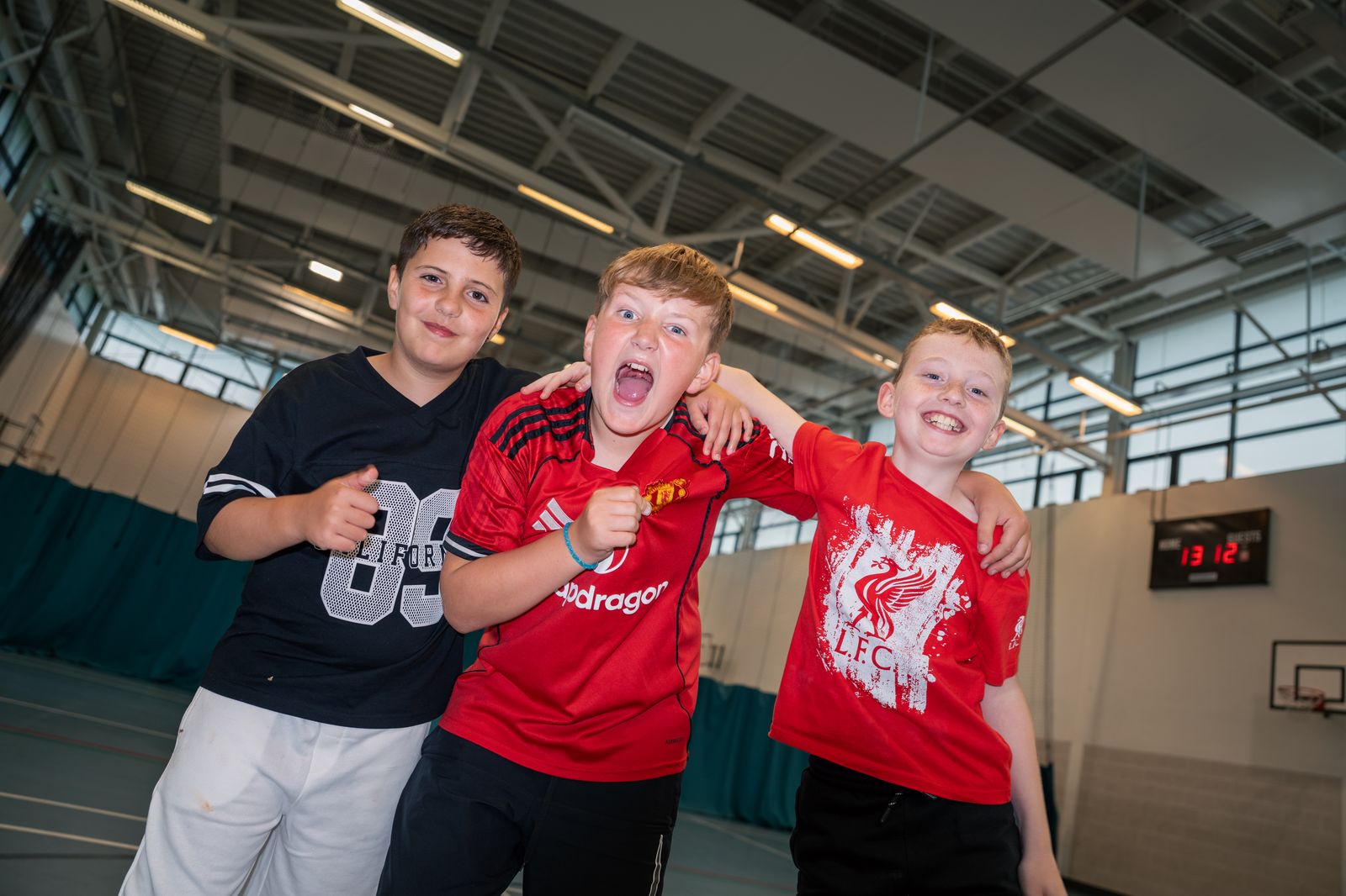 Three members celebrating in the sports hall during the summer programme